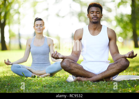 Concentrated yoga students meditating in park Stock Photo