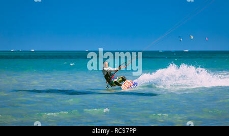 Egypt, Hurghada - 30 November, 2017: The kitesurfer gliding on the Red sea waves. Extreme outdoor activity. The lone man in the sport equipment riding on the water surface. Stunning marine scene. Stock Photo