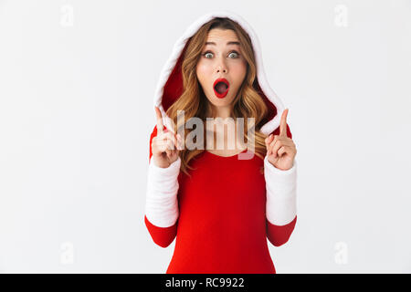 Image of european girl 20s wearing Christmas red dress pointing fingers at copyspace while standing isolated over white background Stock Photo