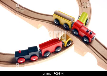 Two toy wooden trains crossing each other at a railroad crossing, railway bridge Stock Photo