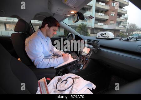 Young GP, general practitioner taking notes in his car after a home visit, car displaying the sign "Arzt im Einsatz" Stock Photo
