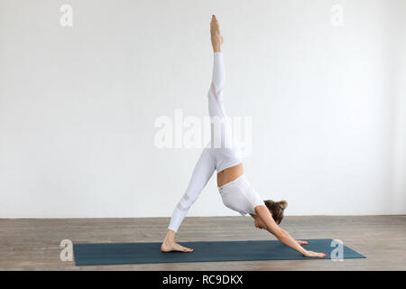 Sporty young woman doing yoga practice on white background at home. Stock Photo