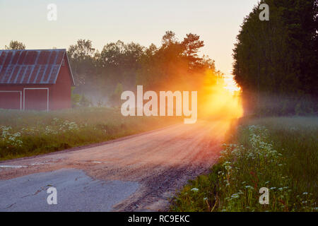 Farmhouse and dirty road at sunset Stock Photo
