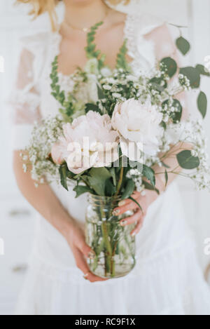 Young woman holding jar of flowers, mid section Stock Photo