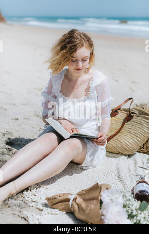 Young woman reading book on beach, Menemsha, Martha's Vineyard, Massachusetts, USA Stock Photo