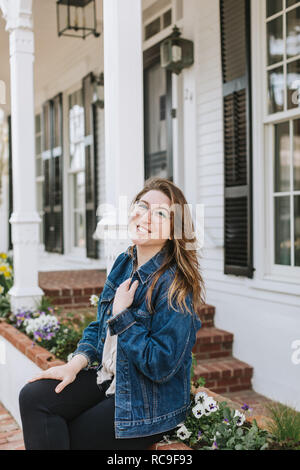 Young woman sitting on village wall, portrait, Menemsha, Martha's Vineyard, Massachusetts, USA Stock Photo