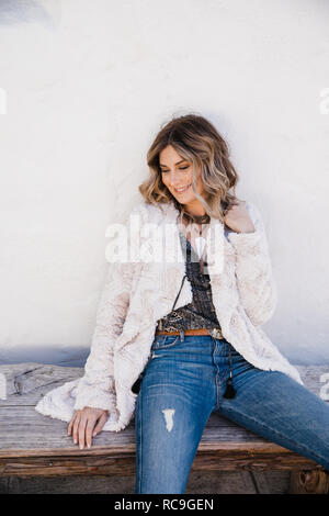 Fashionable woman sitting on wooden bench Stock Photo