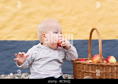 Small boy eating apple from basket Stock Photo