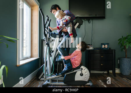 Father and children playing on elliptical machine Stock Photo