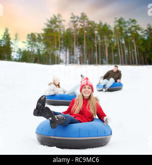 happy friends sliding down hill on snow tubes Stock Photo