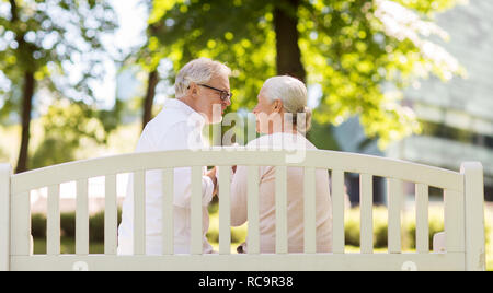 happy senior couple sitting on park bench Stock Photo
