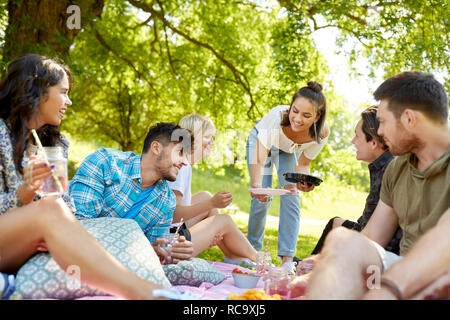 friends with drinks and food at picnic in park Stock Photo
