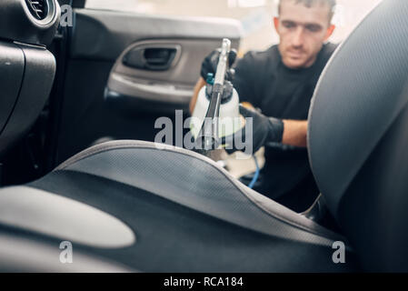 Professional dry cleaning of car interior. Carwash service, worker using spray Stock Photo
