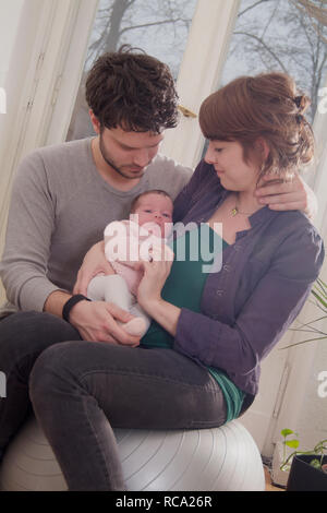 Junge Eltern halten ihre neugeborene Tochter im Arm, das Kind ist 12 Tage alt | young parents holding her new born baby in her arms - the baby ist 12  Stock Photo