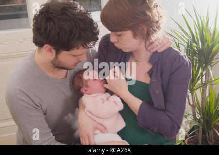 Junge Eltern halten ihre neugeborene Tochter im Arm, das Kind ist 12 Tage alt | young parents holding her new born baby in her arms - the baby ist 12  Stock Photo