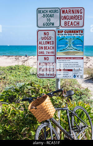 Beach bike leaning against beach warning signs in Palm Beach, Florida. (USA) Stock Photo