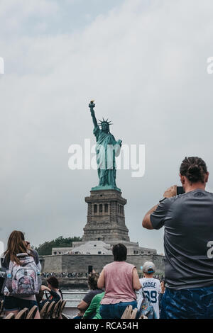 New York, USA - June 02, 2018: Tourists taking photos of Statue of Liberty from a tour boat on Hudson river, New York, USA. New York is one of the mos Stock Photo