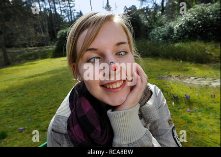 jungendliche Frau mit Marienkäfer auf der Nase | young woman having a beatle on her nose Stock Photo