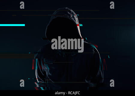 Hooded computer hacker with obscured face, glitch effect Stock Photo