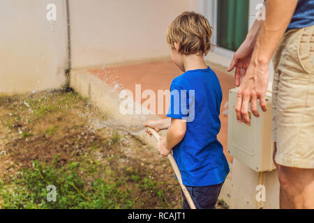 Cute little toddler boy watering plants with watering can in the garden. Adorable little child helping parents to grow vegetables and having fun. Activities with children outdoors Stock Photo