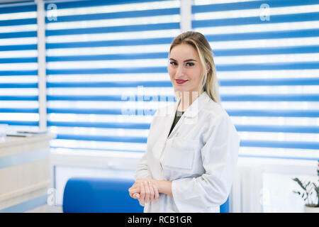 Portrait of young woman doctor with white coat standing in hospital Stock Photo