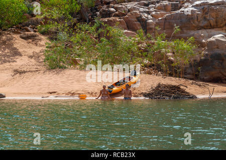 Young couple with kayak sitting on sandy beach in the Katherine Gorge, Nitmiluk National Park, Katherine, Northern Territory, Top End, Australia