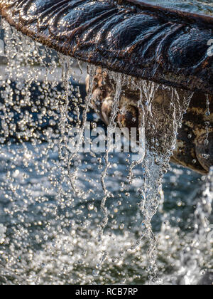 WATER FOUNTAIN DROPS DROPLETS Water flowing off an ornamental old weathered limestone garden feature water fountain in bright sunlit situation Stock Photo