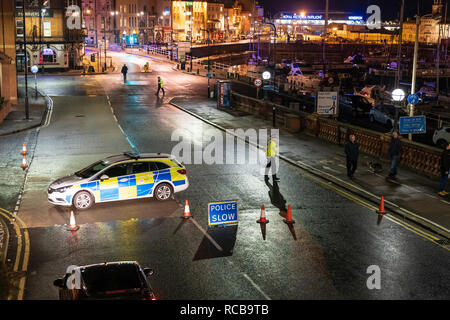 Ramsgate bomb suspected bomb incident on 14 January 2019. Police cars with blue flashing lights help cordon off the harbour road, night time. Three police cars and some policemen parked on approach road to seafront and harbour. 'Police slow' sign. Stock Photo