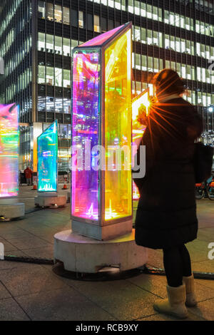 Canary Wharf, London, UK, 14th Jan 2019. People look at the revolving columns of the 'Prismatica' installation in Jubilee Square. The colourful Canary Wharf Winter Lights installations once again open to public viewing and interactive fun in and around Canary Wharf from Jan 15th until Jan 26th. Credit: Imageplotter News and Sports/Alamy Live News Stock Photo