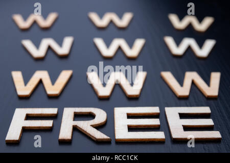 The inscription is arranged from letters cut out of wood on the table. The word – www free. Dark background. Stock Photo