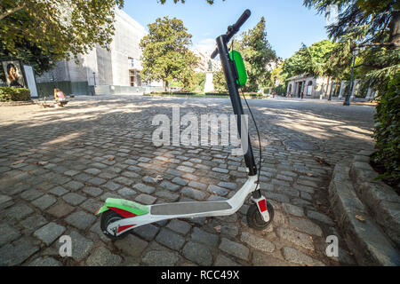 Dockless electric kick scooters from a scooter-sharing system parked on a sidewalk. One vehicule for rent at Madrid old town Stock Photo
