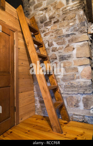 Pinewood Miller's stairs leading to bed located on the mezzanine of attic bedroom inside an old circa 1752 Canadiana style fieldstone home. Stock Photo