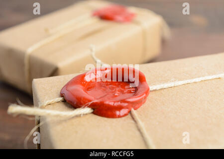 Gifts in craft paper with sealing wax over brown wooden table Stock Photo