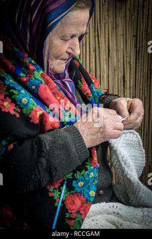 Verona, Italy - December 26, 2018: Detail of an old lady knitting a wool blanket. Stock Photo