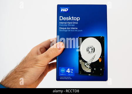 PARIS, FRANCE - FEB 21, 2018: Man holding against white background blue box with new HDD Hard Disk Drive internal from Western Digital upgrading computer Stock Photo