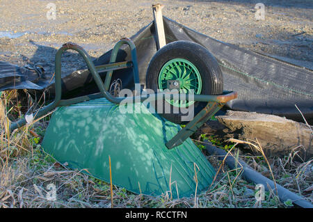 An green abandoned wheelbarrow upside down in an empty construction site in British Columbia, Canada. Stock Photo