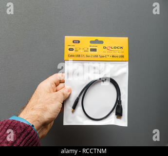 PARIS, FRANCE - JAN 23, 2018: Man holding USB 3 Gen 2.1 USB Type-C to Micro USB adapter against gray background  Stock Photo