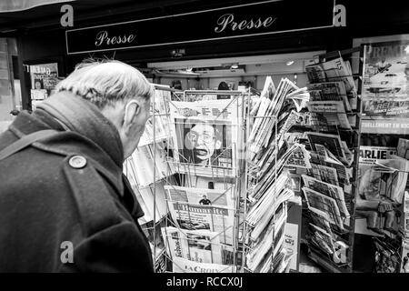 PARIS, FRANCE - MAR 15, 2018: Senior man buying French newspaper Liberation at Parisian press kiosk featuring Stephen Hawking portrait  black and white  Stock Photo