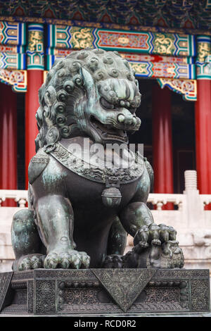 Stone, Chinese lion statue in front of red columns of the forbidden city in Beijing China Stock Photo