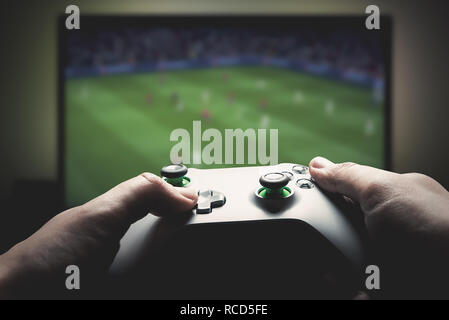 Man is playing on the console. Man holding gamepad and playing soccer game Stock Photo