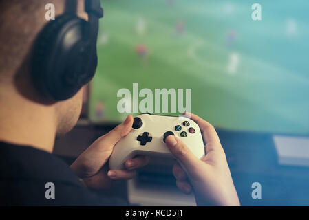 Man is playing on the console. Man holding gamepad and playing soccer game Stock Photo