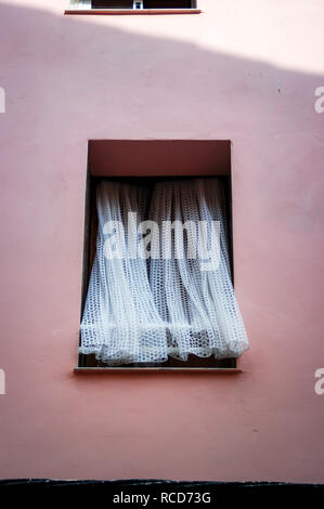 Pink rendered wall with Net Curtains blowing in the breeze from the open window Stock Photo