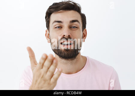 Showing passion and affection to woman of heart guy sending passionate kiss sending it with palm near lips gazing romantic and delighted at camera being in love, posing in pink t-shirt over white wall Stock Photo