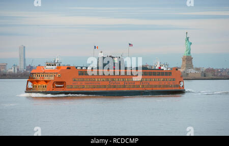 The MV Andrew J. Barberi Staten Island Ferry passes the statue of liberty as it travels from Manhattan to Staten Island in New York, New York City, NY Stock Photo