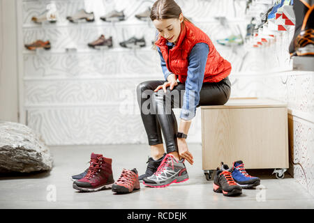 Woman trying shoes for mountain hiking sitting in the room of the modern sports shop Stock Photo - Alamy