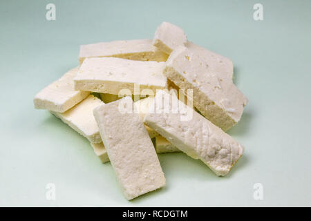 Sliced cheese or paneer on light green background Stock Photo