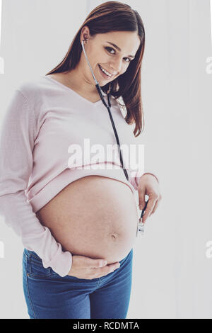 Young pregnant woman's belly being checked by a doctor using a