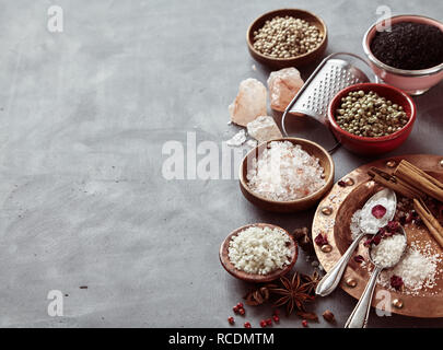 Border of natural cooking salts from around the world and aromatic spices on a mottled grey background with copy space Stock Photo