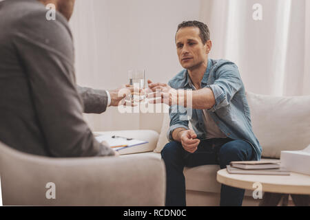 Man in depression sitting in the office of therapist Stock Photo