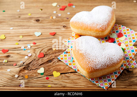 Heart-shaped cookies on colorful napkins in close-up on rustic wooden table with confetti. Easter treat concept with copy space Stock Photo